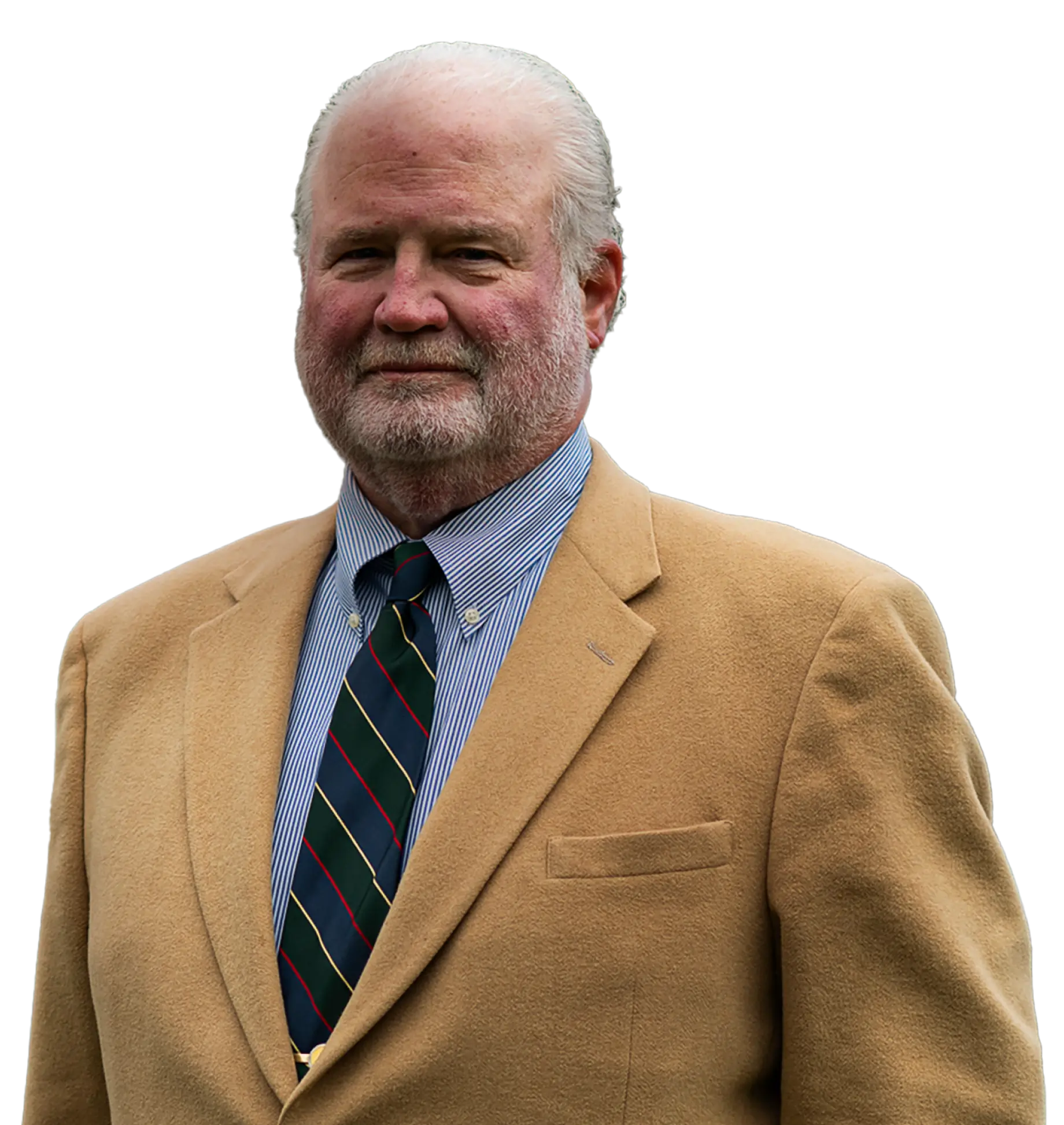 An older man with a white beard and mustache is wearing a tan suit jacket, a striped tie, and a blue and white striped shirt. He is standing against a plain background, looking slightly to the side with a neutral expression.