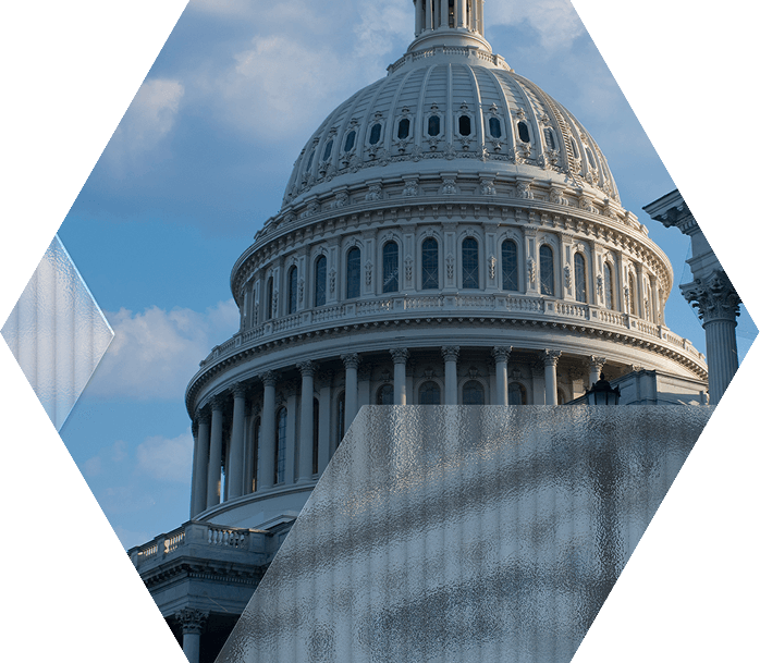 A hexagon-shaped image of the U.S. Capitol dome against a blue sky, partially overlaid with semi-transparent, frosted geometric shapes in the foreground.