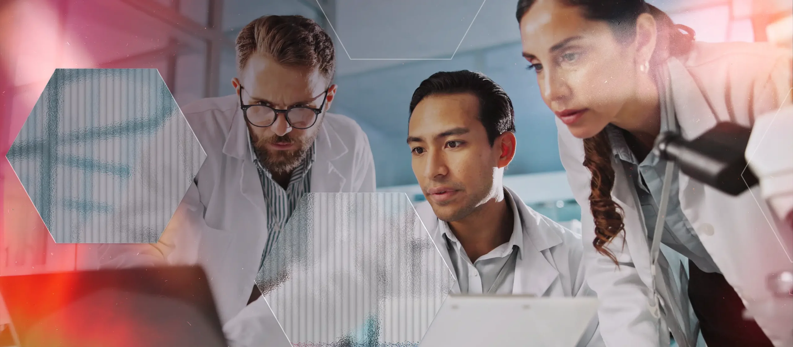 Three scientists in lab coats closely examine information on a laptop, appearing focused and engaged. Laboratory equipment and hexagonal graphics are visible in the background.