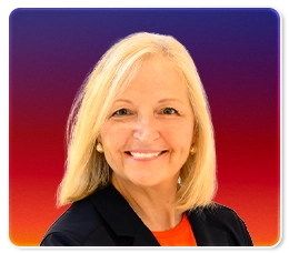 A smiling woman with straight blonde hair wearing a dark blazer and an orange top, posed in front of a gradient background transitioning from purple to red.